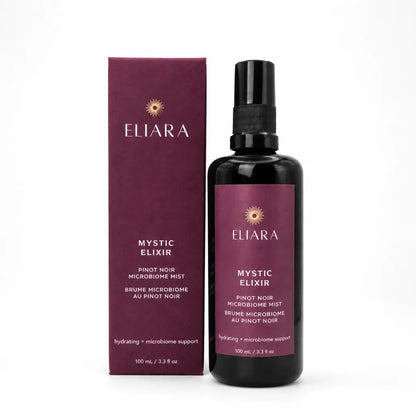 A bottle of Eliara Mystic Elixir Pinot Noir Microbiome Mist next to its matching dark purple box, set against a plain white background.